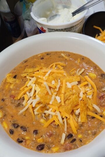 Taco Soup topped with sour cream, cheese and tortilla strips