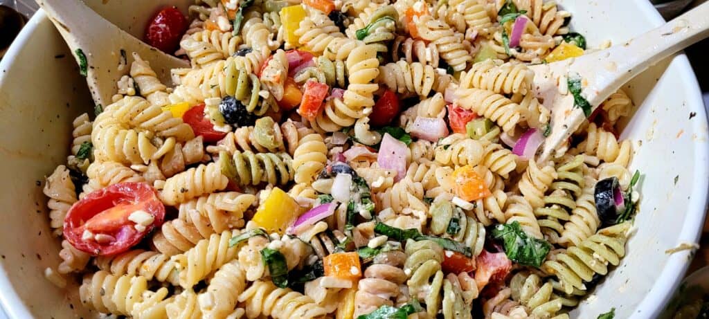 Easy Pasta Salad in a bowl with serving utensils on the side