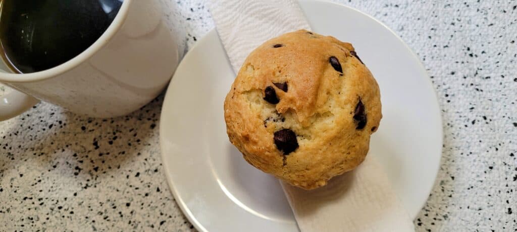 Plated chocolate chip muffin with a cup of coffee