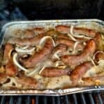Beer Brats with onions in a pan on the grill