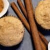 two cinnamon muffins with a bowl of brown sugar and a bowl of cinnamon and 3 cinnamon sitcks
