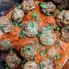 air fryer meatballs in a pot of marinara sauce, topped with fresh parsley