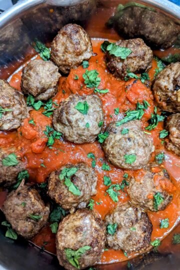 air fryer meatballs in a pot of marinara sauce, topped with fresh parsley