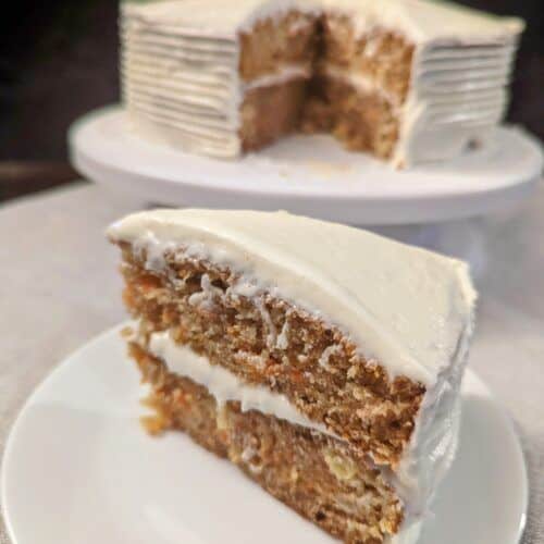 Carrot cake slice in front a cut carrot cake