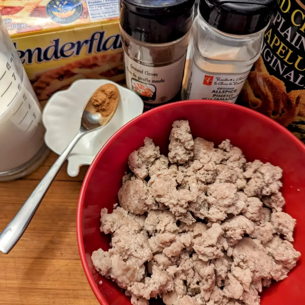 Ingredients for making Cretons: Bowl of cooked ground pork, cinnamon, cloves, all spice, bread crumbs, milk and lard