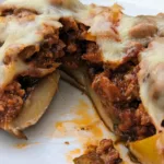 Stuffed portobello mushroom cut open to see the inside which is chorizo and peppers and topped with melted mozzarella cheese.