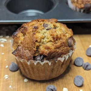 Oatmeal Chocolate Chip muffin with chocolate chips and oatmeal on a wooden cutting board
