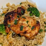 Gochujang chicken thigh on a bed of rice and broccoli, topped with chopped green onion.