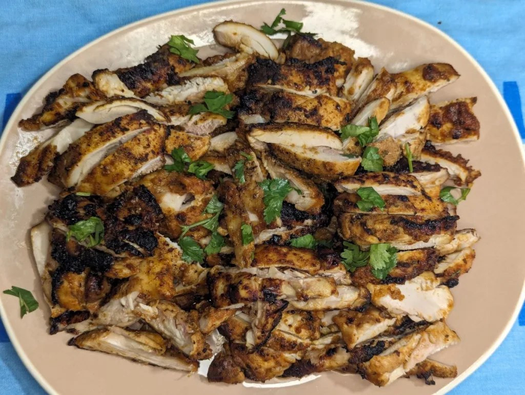 Plate of sliced grilled Mexican chicken with cilantro pieces on top