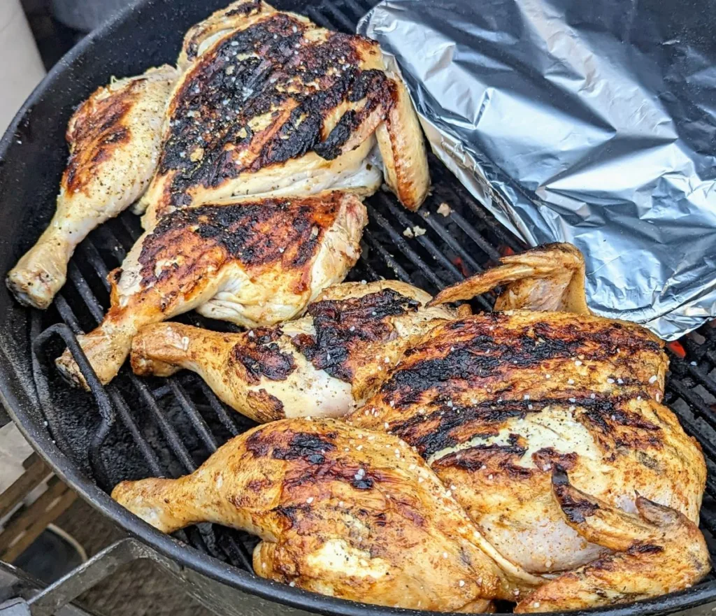 Two spatchcock chickens on a charcoal grill