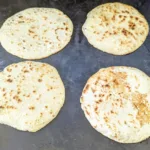 four tortillas cooking on a blackstone
